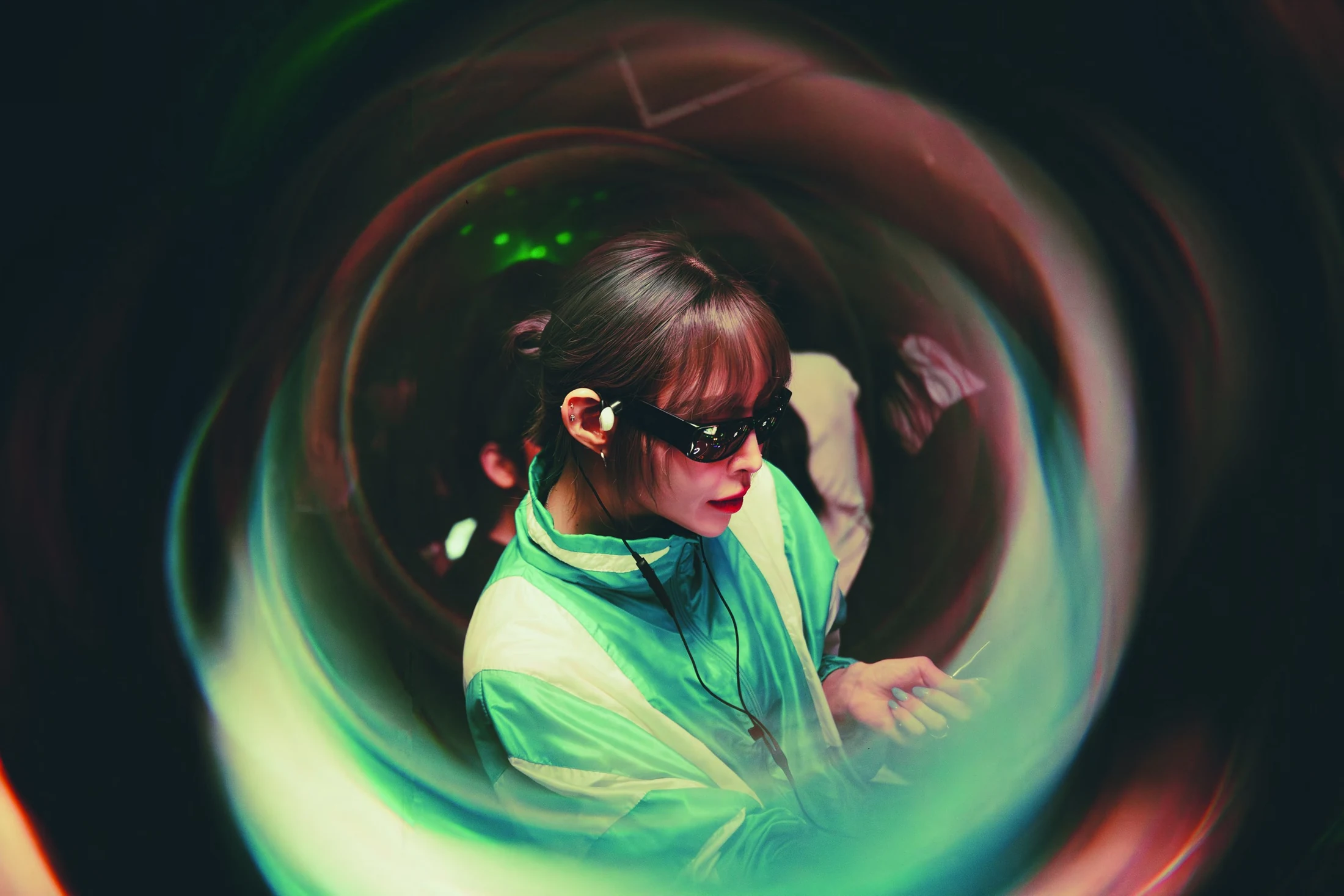 YOONI performing in a green jacket, surrounded by circular light trails